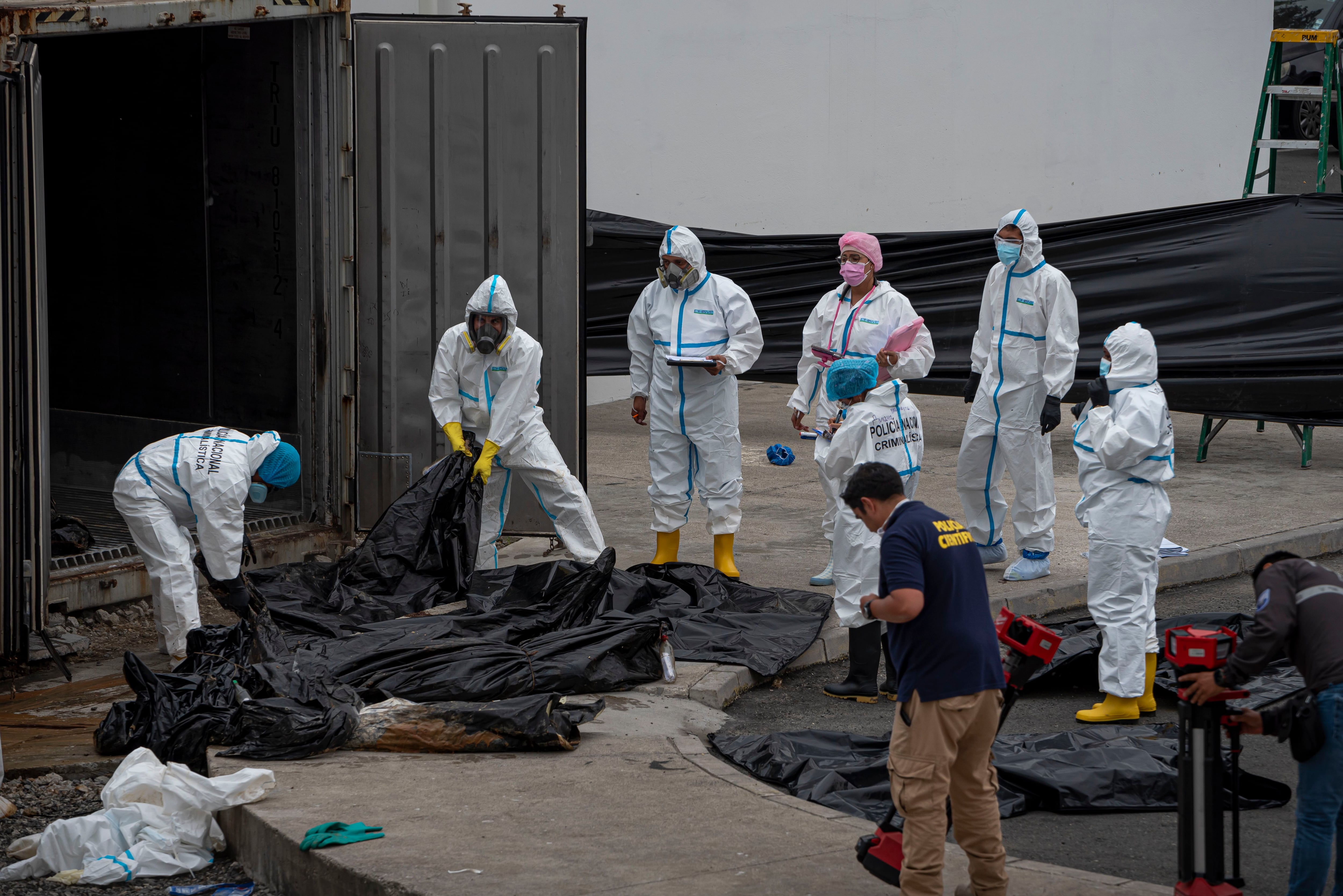 Agentes de criminalística trabajan con los cadáveres acumulados en los contenedores de la morgue de Guayaquil, el 12 de junio.